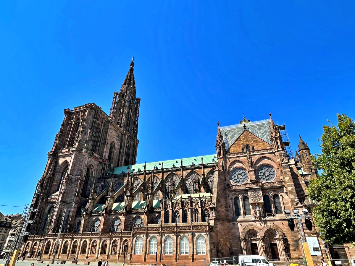 Vista lateral de la Catedral de Notre-Dame de Estrasburgo con fachada gótica y torre campanario bajo cielo azul