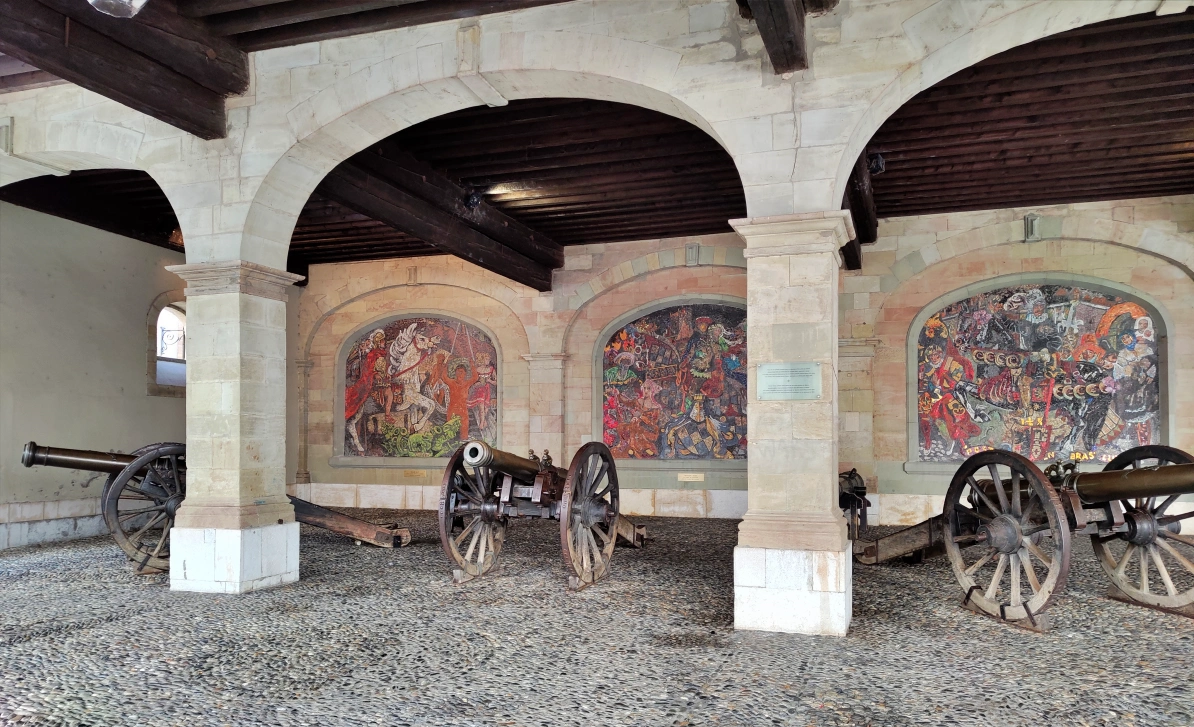 Fachada porticada de L’Ancien Arsenal de Ginebra con cañones antiguos y mosaicos históricos en el casco antiguo