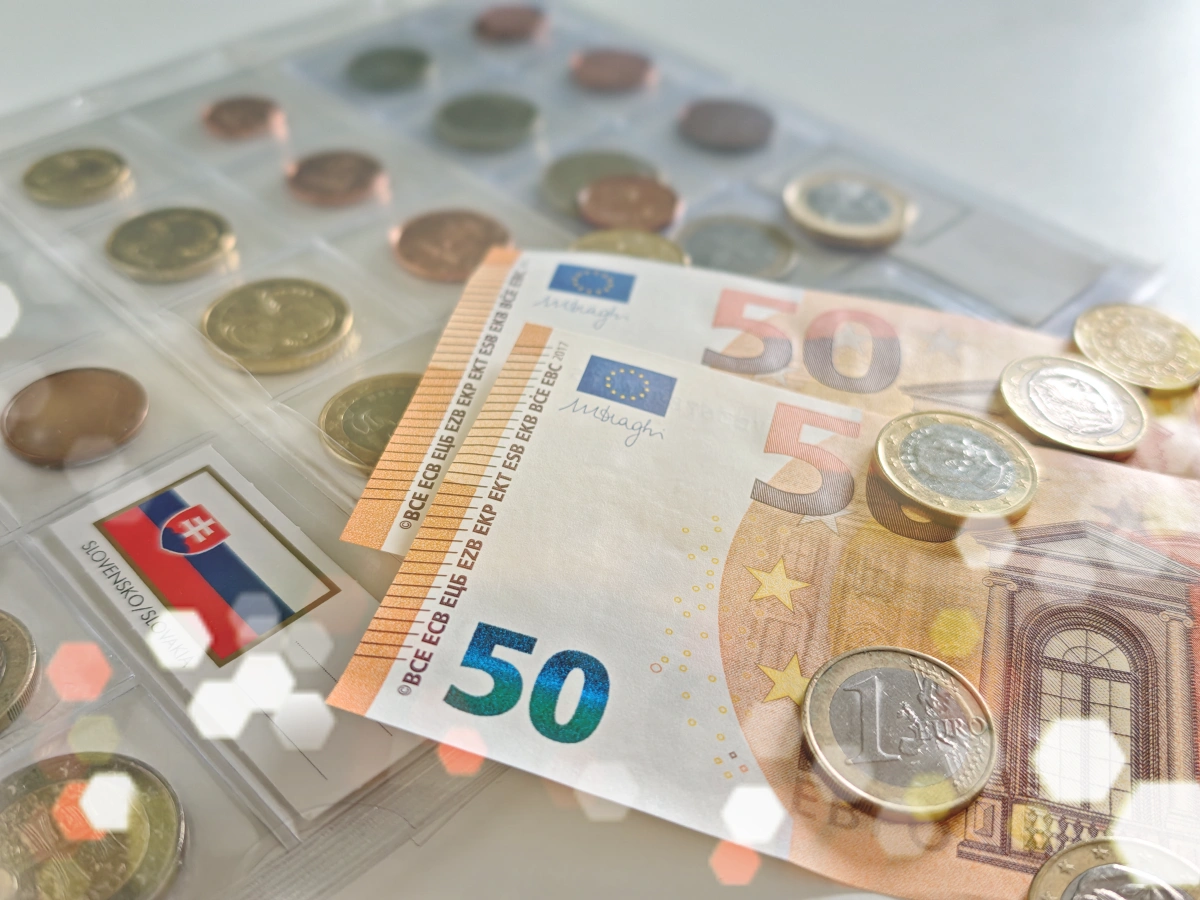 Detalle de monedas y billetes de euro junto a una colección de monedas de Eslovaquia en un álbum numismático