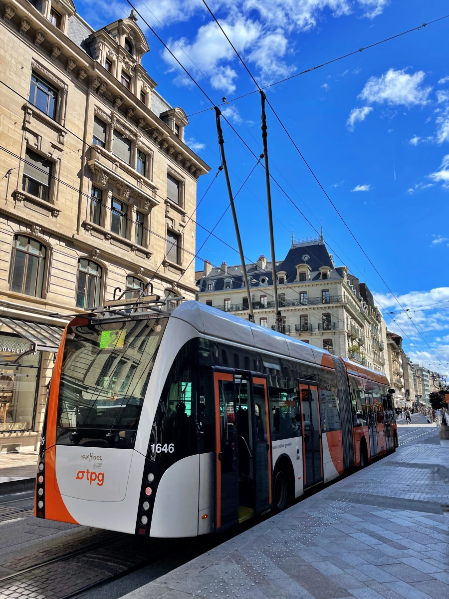 Trolebús de la red TPG en Ginebra circulando por la ciudad con las iniciales TPG visibles en la carrocería roja y blanca