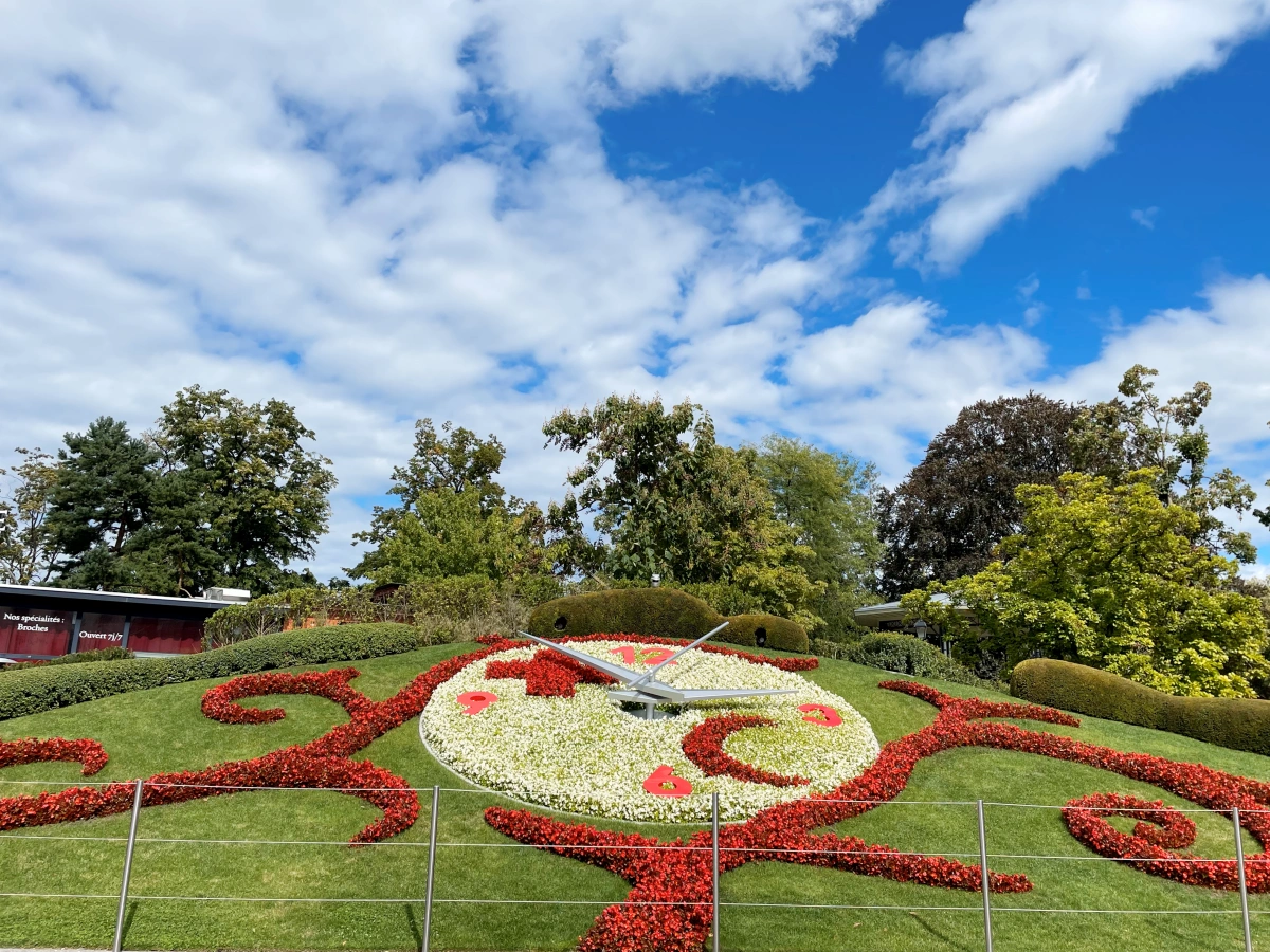 Vista frontal del Reloj de Flores de Ginebra con diseño floral colorido y agujas doradas, ubicado en el Jardín Inglés junto al lago Lemán