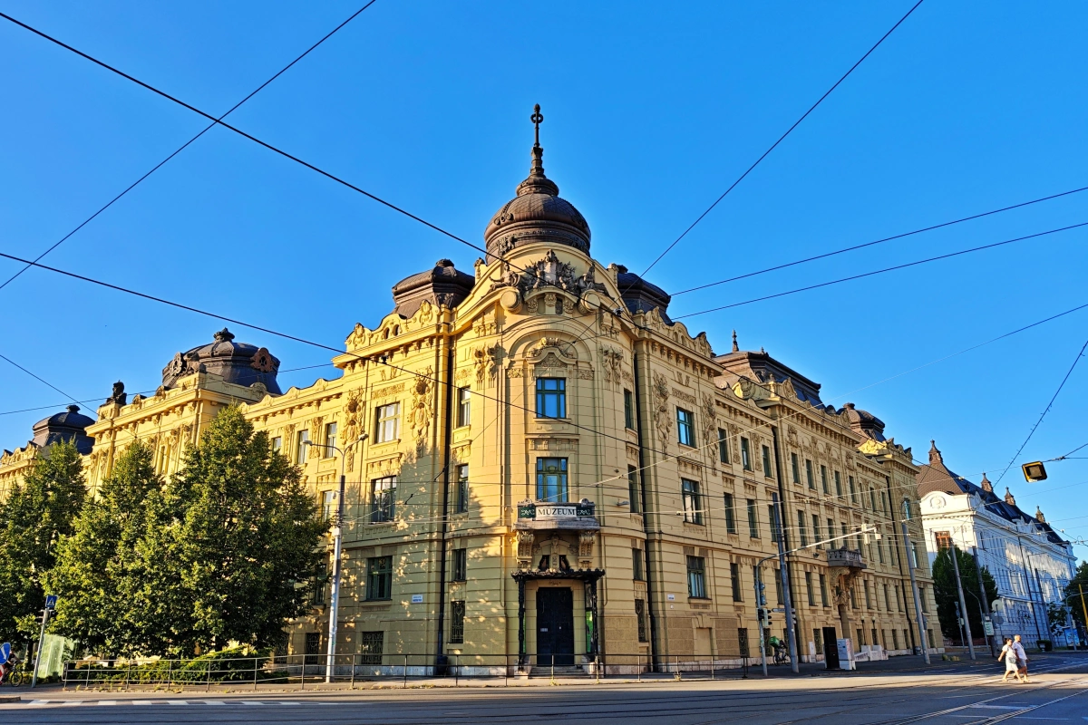 Fachada principal del Museo del Este de Eslovaquia (Východoslovenské múzeum) en Košice, Eslovaquia, con arquitectura neorrenacentista de principios del siglo XX, edificio amarillo con cúpula central y esculturas de Perseo y Vulcano, ubicado en la Plaza del Maratón de la Paz.