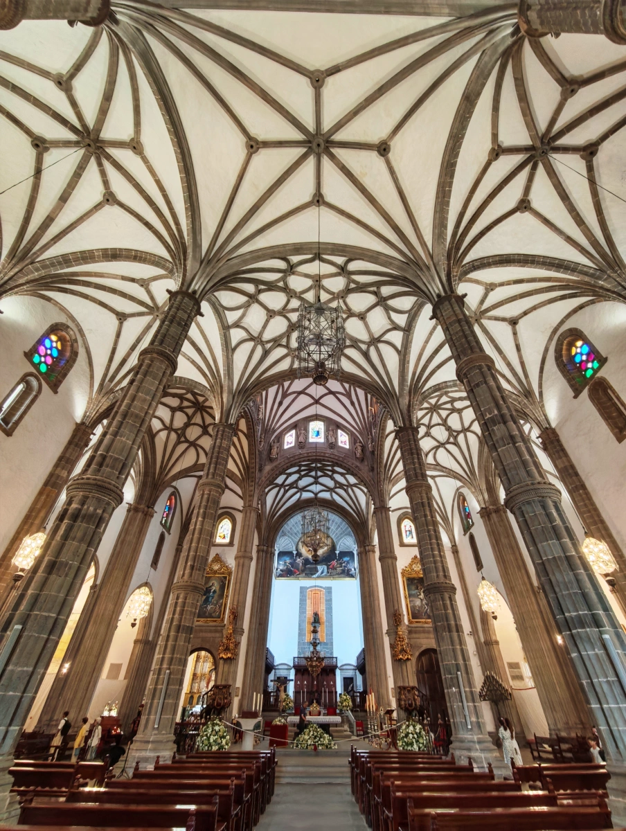 Detalle del interior de la Catedral de Santa Ana con bóvedas góticas, columnas robustas y vitrales iluminando el altar en Las Palmas.