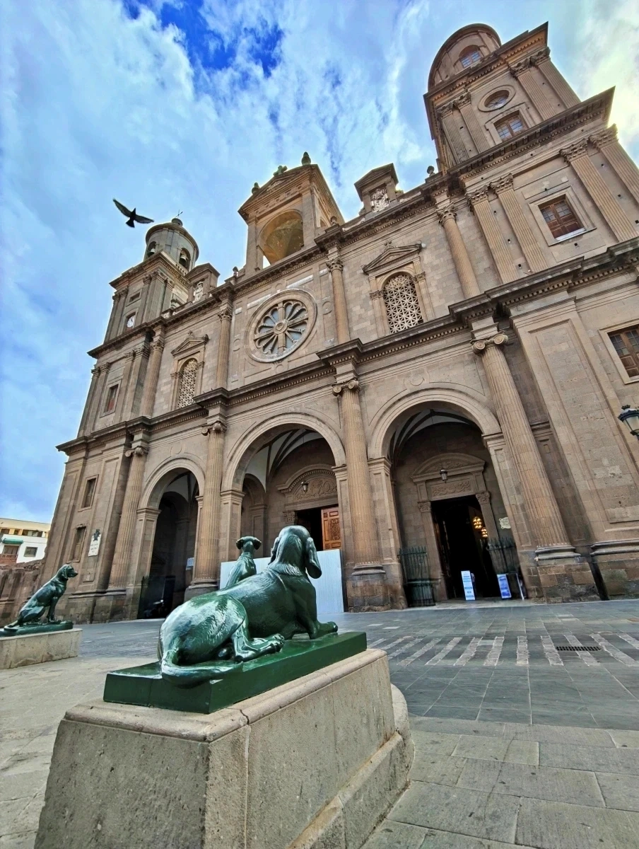 Primer plano de esculturas de perros en la Plaza de Santa Ana con la Catedral de Santa Ana al fondo bajo un cielo azul en Las Palmas de Gran Canaria.