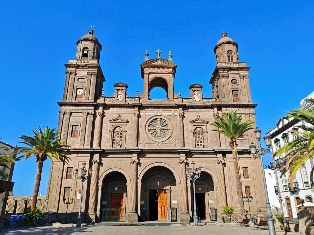 Vista frontal de la Catedral de Santa Ana, destacando su imponente arquitectura neoclásica y las palmeras de la plaza en Las Palmas de Gran Canaria.