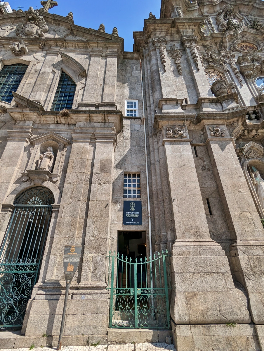 Detalle de la estrecha Casa Escondida con puerta verde entre dos iglesias barrocas