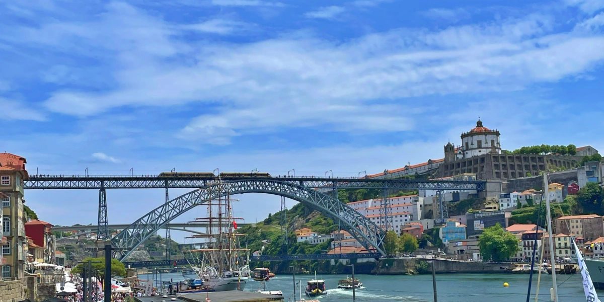 Vista de la ribera de Oporto con barcos en el Duero, el Puente de Don Luis I y el monasterio de la Serra do Pilar al fondo