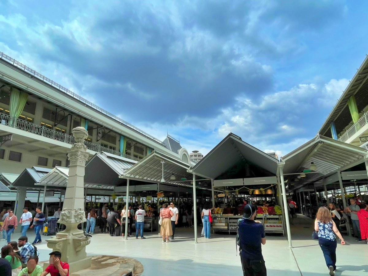 Pasillo del Mercado do Bolhão con puestos de frutas, hortalizas y clientes