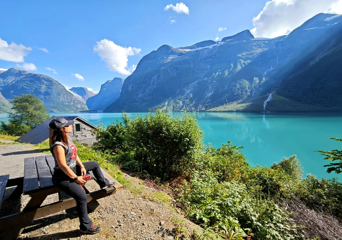 Mujer viajera sentada junto al lago Lovatnet rodeado de montañas en Noruega