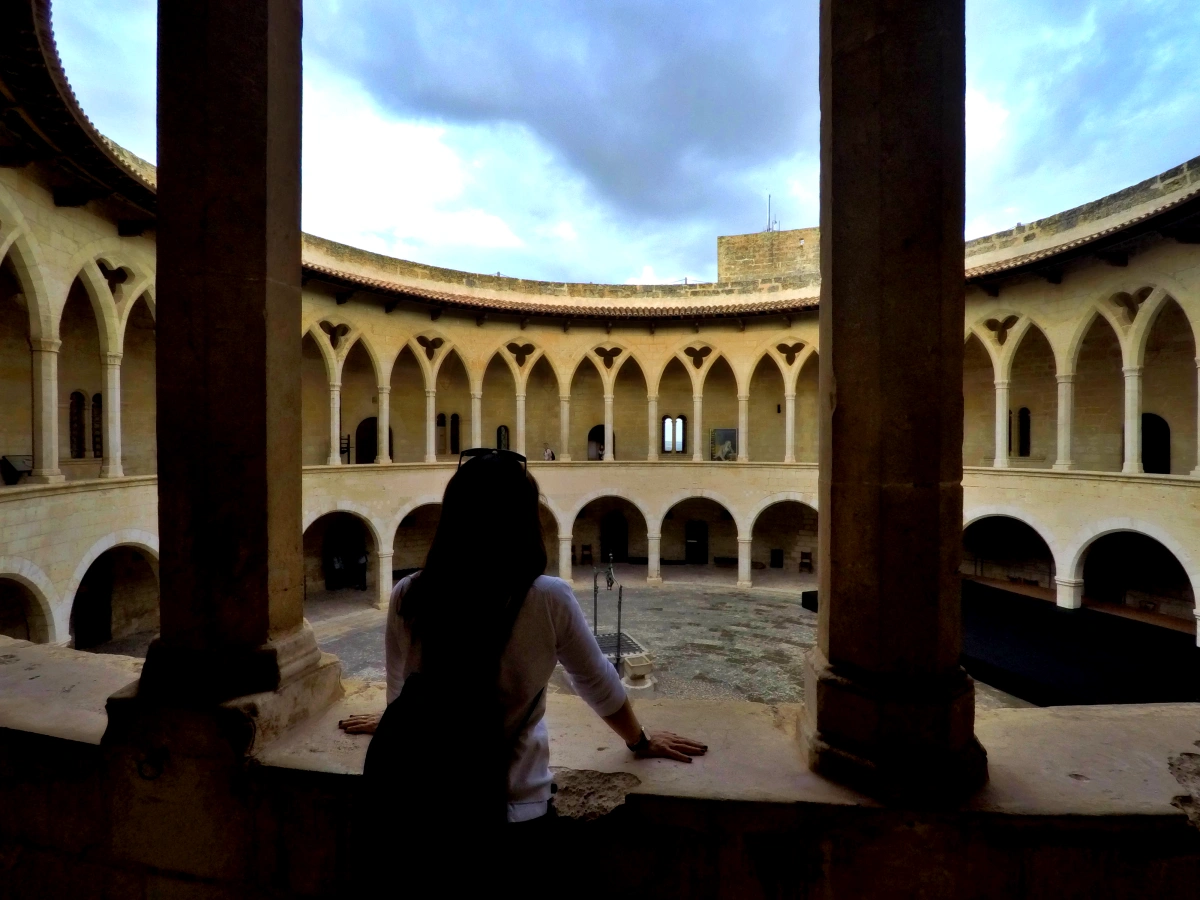 Persona observando el patio circular gótico del Castillo de Bellver en Mallorca