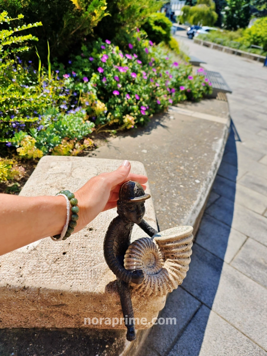 Mini escultura de bronce de Ödön, músico callejero creado por Kolodko en Veszprém, sentado con un caracol en la mano