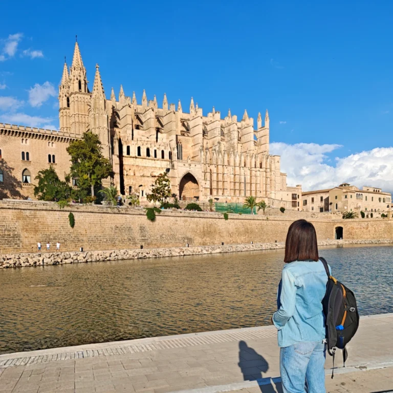 Vista de la Catedral de Palma reflejada sobre el Parc de la Mar, con visitante admirando el monumento
