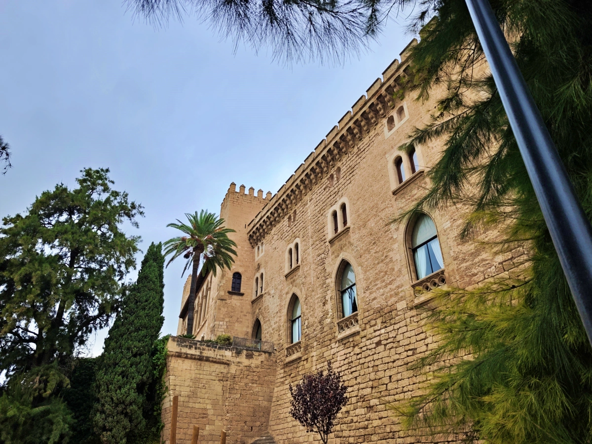 Lateral del Palacio Real de la Almudaina rodeado de jardines y palmeras