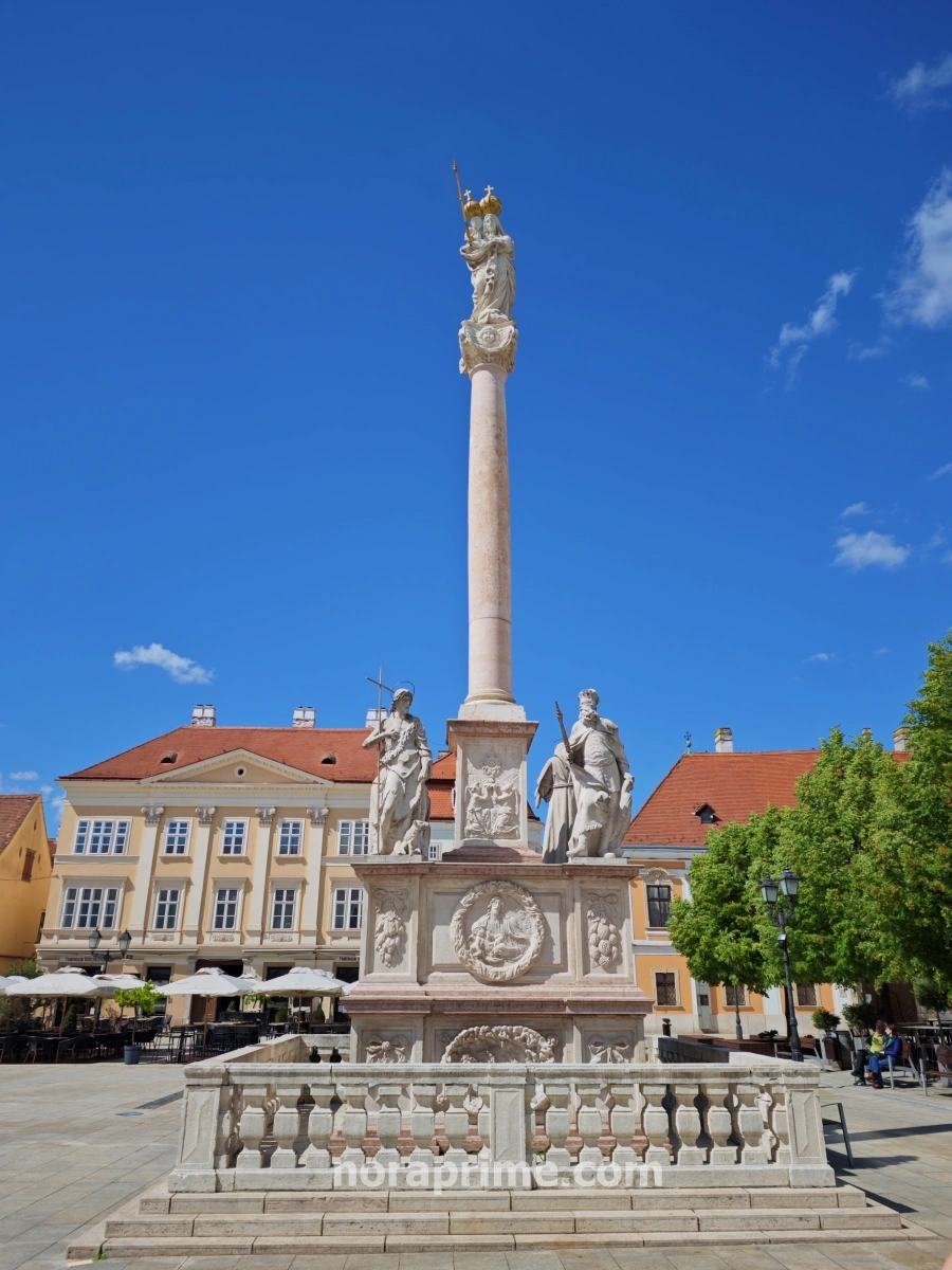 Columna de la Virgen María y el Niño en la plaza principal de Györ, rodeada de arquitectura barroca