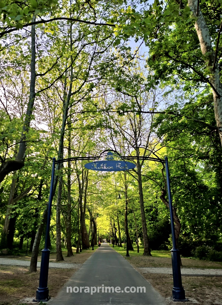 Pórtico azul de entrada al Helikon Park en Keszthely, rodeado de árboles y senderos