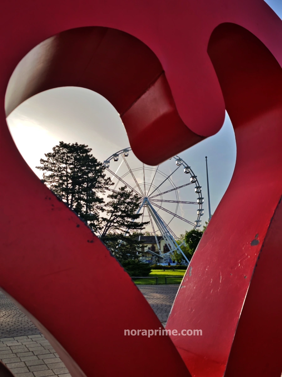 Noria panorámica captada a través del corazón rojo del letrero de Keszthely, playa lago Balaton