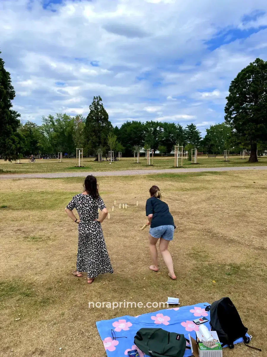 Grupo de chicas jugando al Mölkky en el césped del Seepark junto al lago Flückiger, actividad recreativa popular en Friburgo