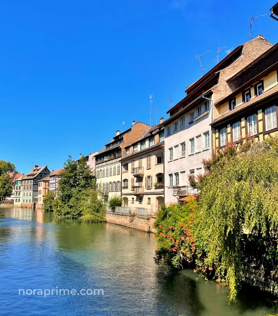 Vista desde el Pont du Faisan en la Petite France de Estrasburgo con canal, flores y casas tradicionales