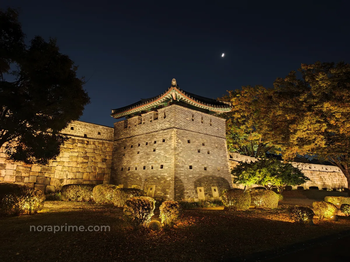Muralla y torre de vigilancia de la fortaleza de Hwaseong en Suwon iluminadas por la noche en otoño