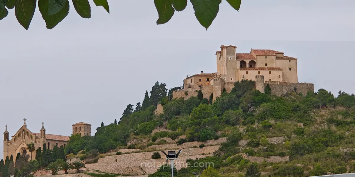 Panorámica del Santuario de Sant Salvador de Artà, complejo amurallado en la cima de una colina con iglesia y torres, rodeado de terrazas y vegetación mediterránea en el noreste de Mallorca.