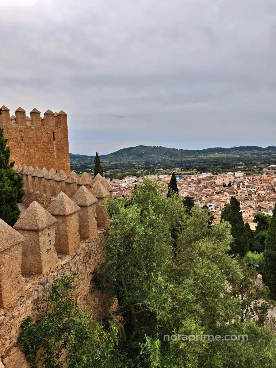 Vista del casco antiguo de Artà desde las murallas fortificadas de Sant Salvador, con tejados de teja, cipreses y montañas al fondo en Mallorca.